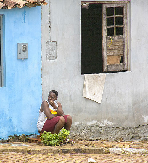 Woman sitting by house on street